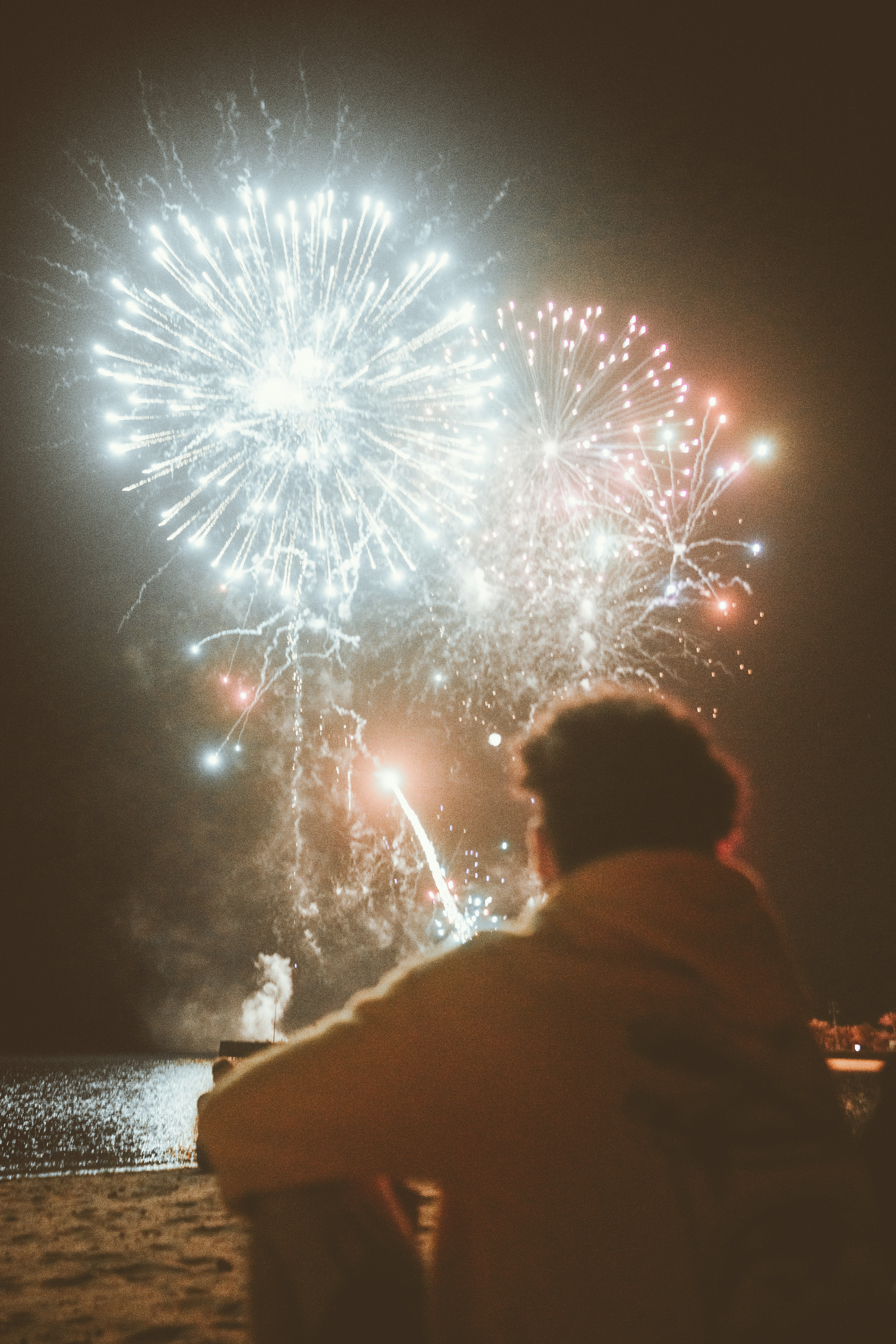 a man sitting on a bench watching fireworks