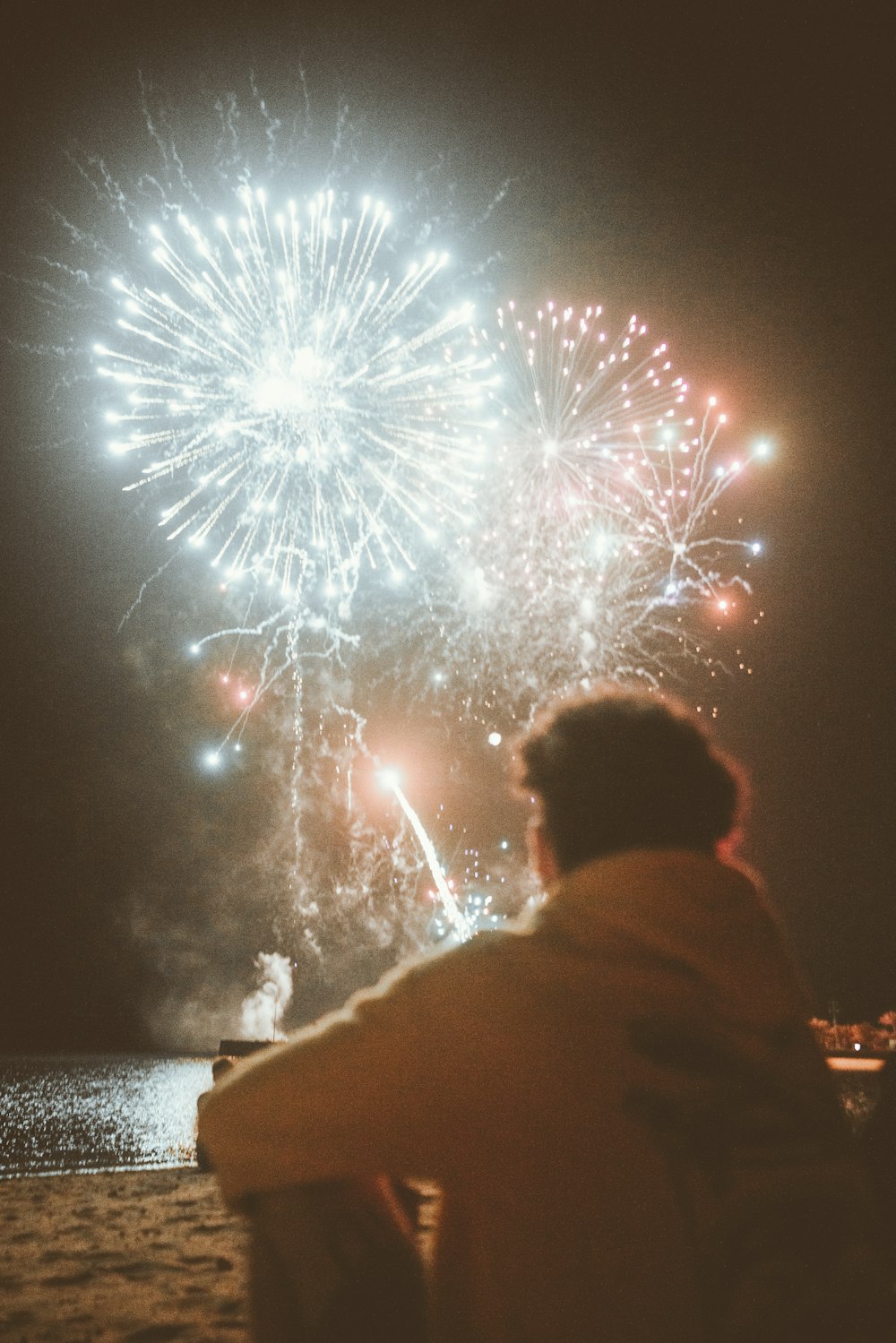 a man sitting on a bench watching fireworks