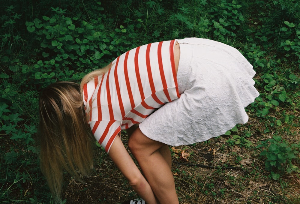 a woman bending over in a field of grass
