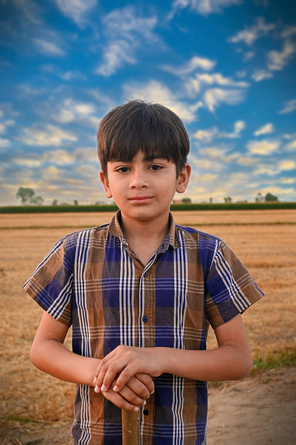 a young boy standing in front of a field