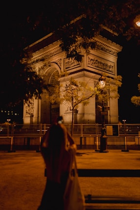 a woman is standing in front of a building at night
