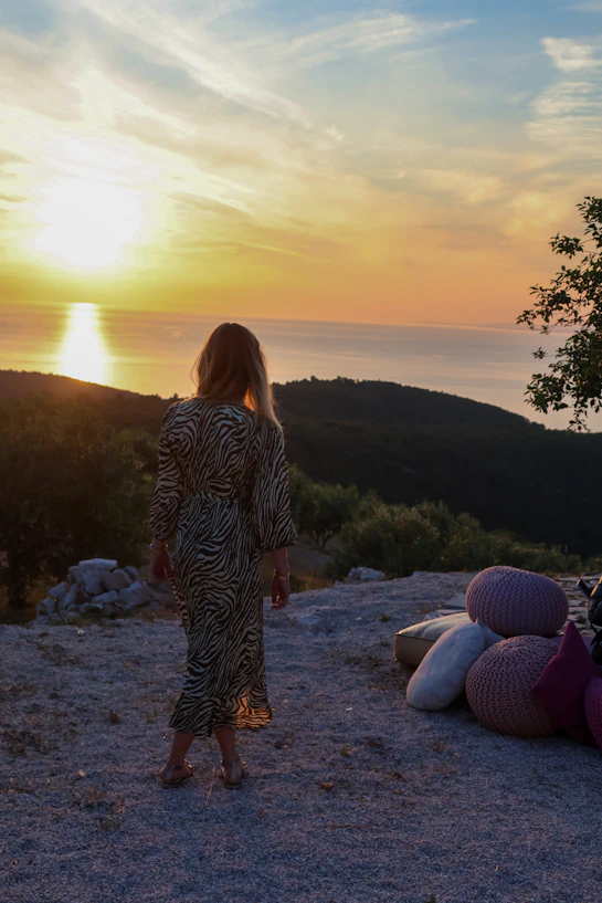 a woman standing on top of a hill next to a pile of pillows