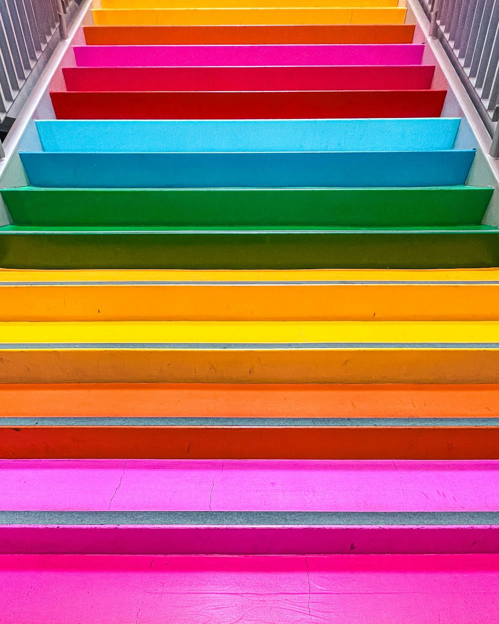 a multicolored staircase with a metal hand rail