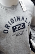 a gray shirt with a black and white logo on it