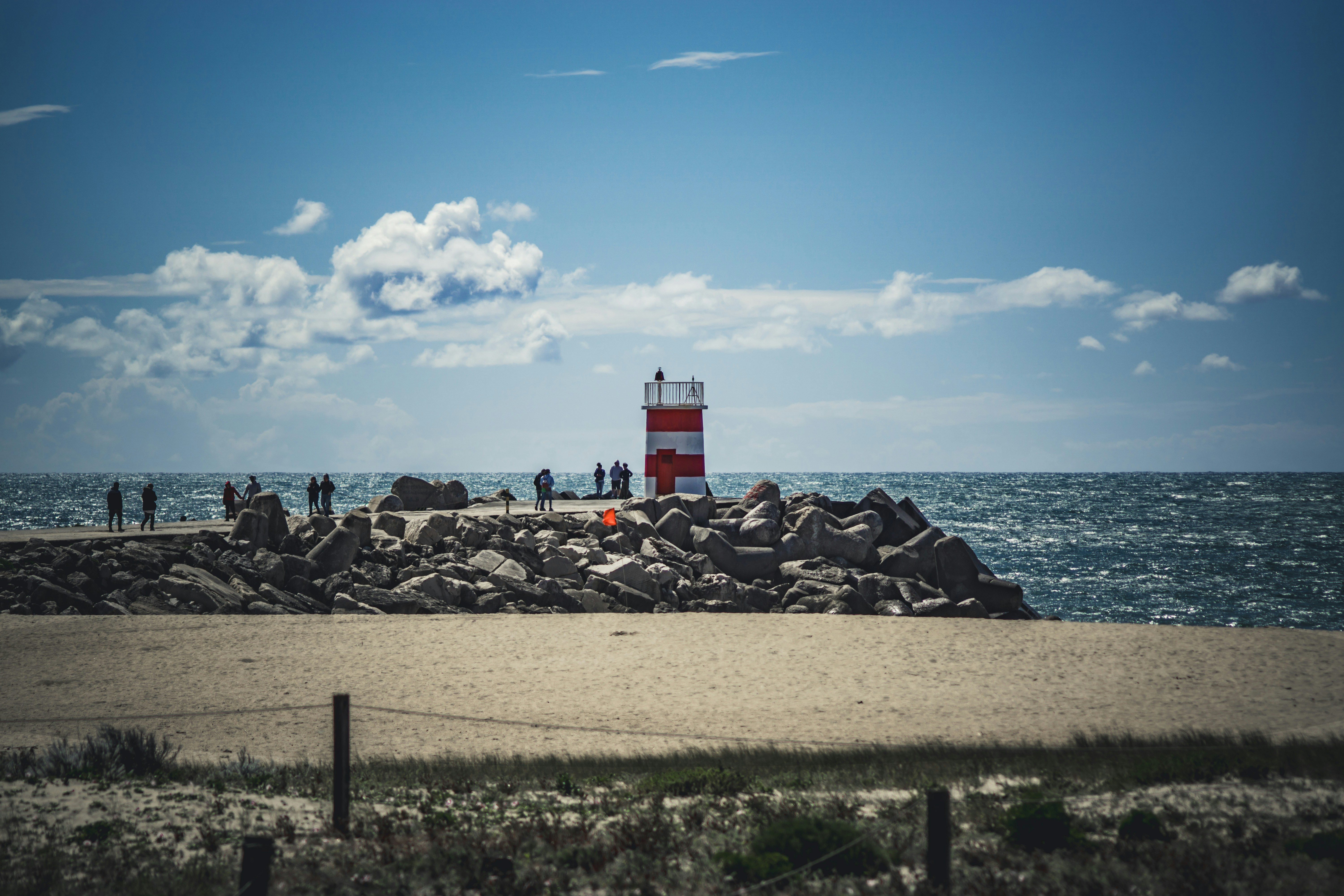 a red and white lighthouse sitting on top of a sandy beach