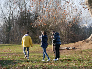 Three people walking in a park during autumn.