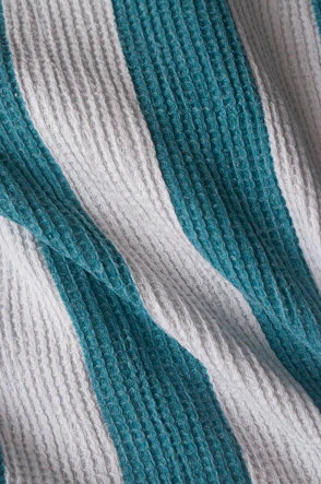 a blue and white striped blanket laying on top of a bed