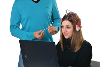 a man standing next to a woman using a laptop