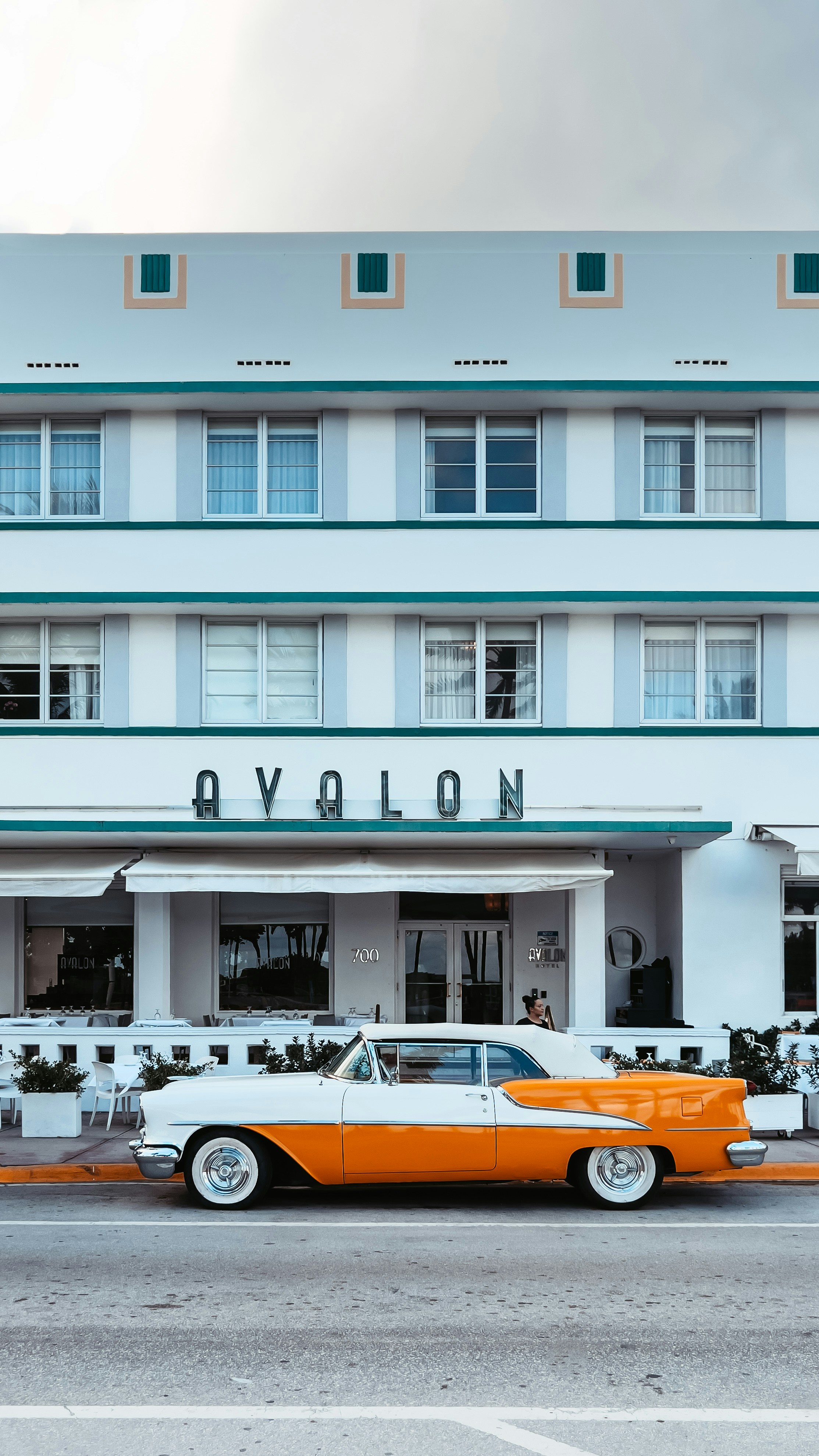 Sebuah mobil oranye dan putih diparkir di depan hotel