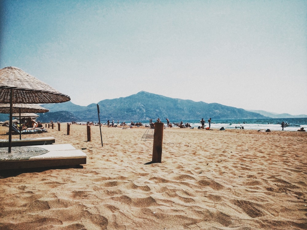 une plage de sable avec des parasols et des gens dessus