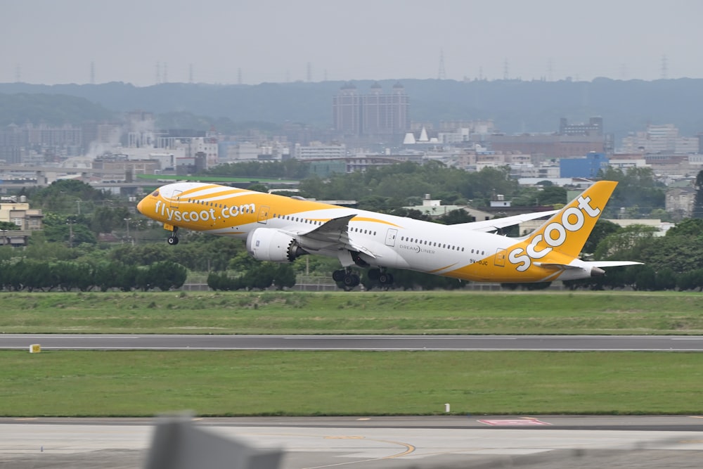 a yellow and white plane taking off from a runway