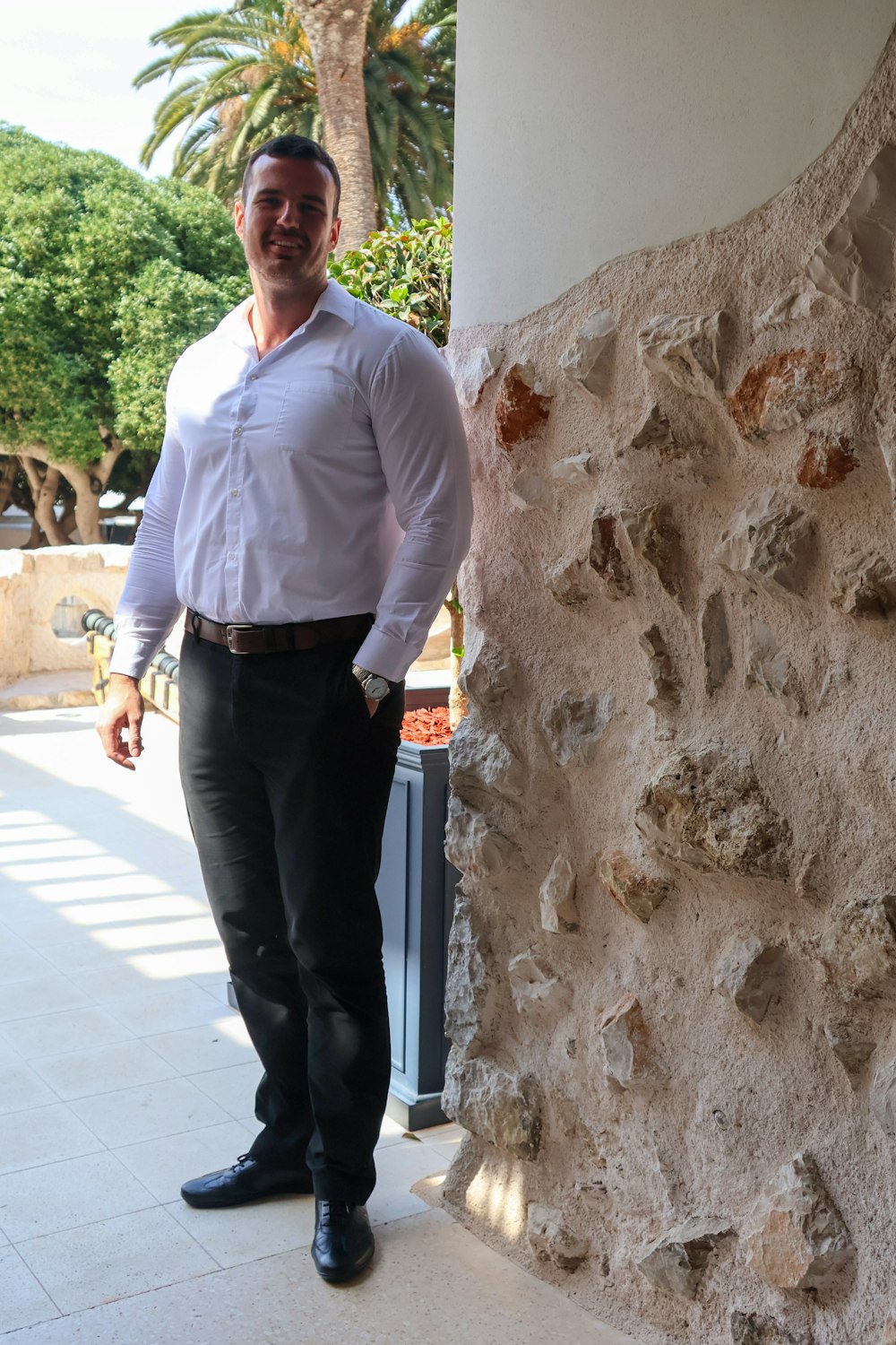 un uomo in piedi accanto a un muro di pietra