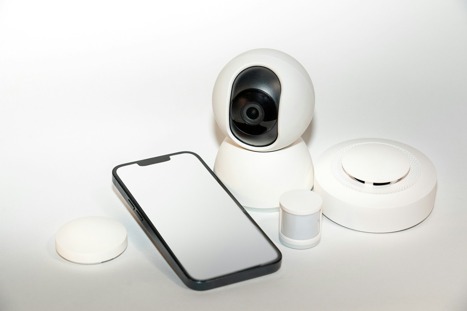 A smartphone beside a small indoor security camera