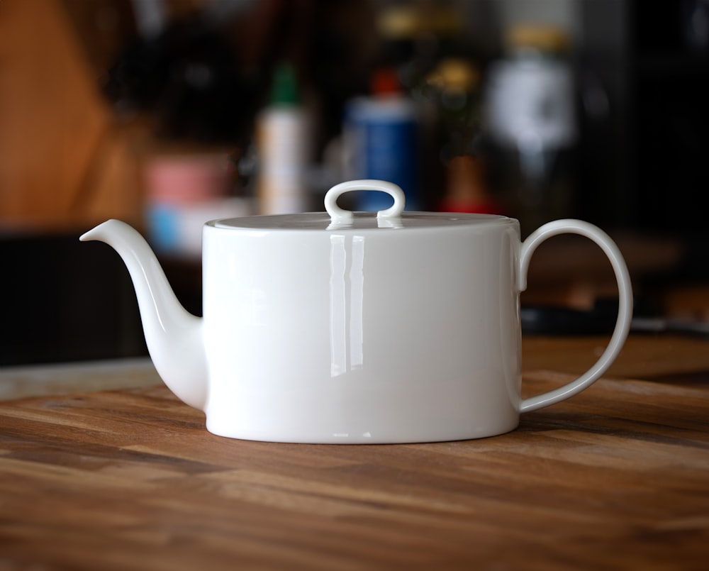 a white tea pot sitting on top of a wooden table