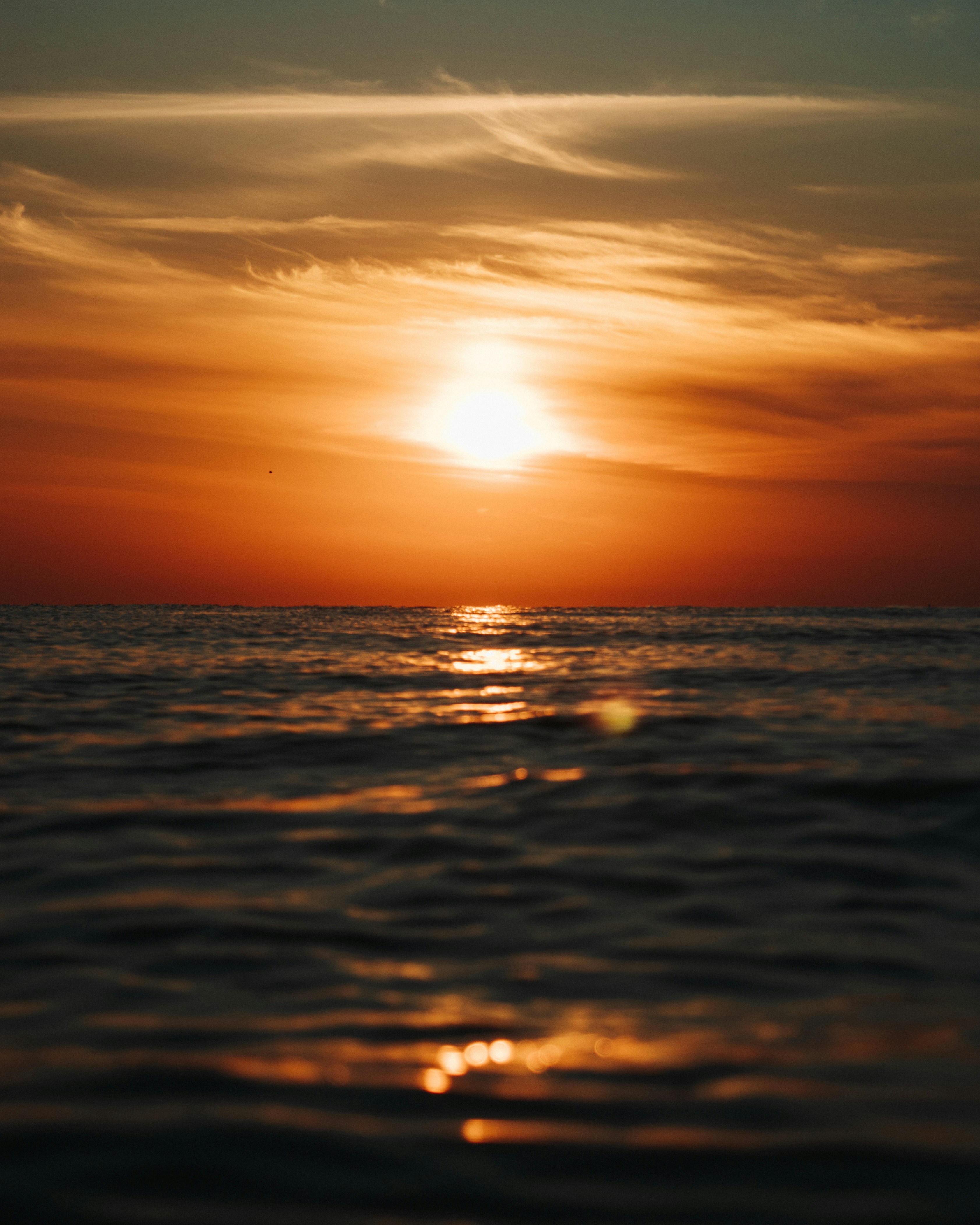 the sun is setting over the ocean on a cloudy day