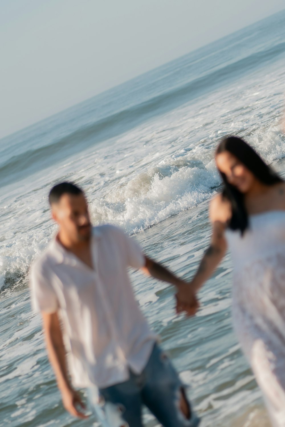 a man and a woman holding hands on the beach