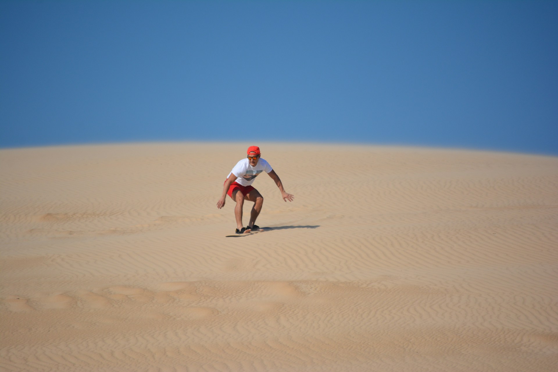 a man riding a skateboard down a sandy hill
