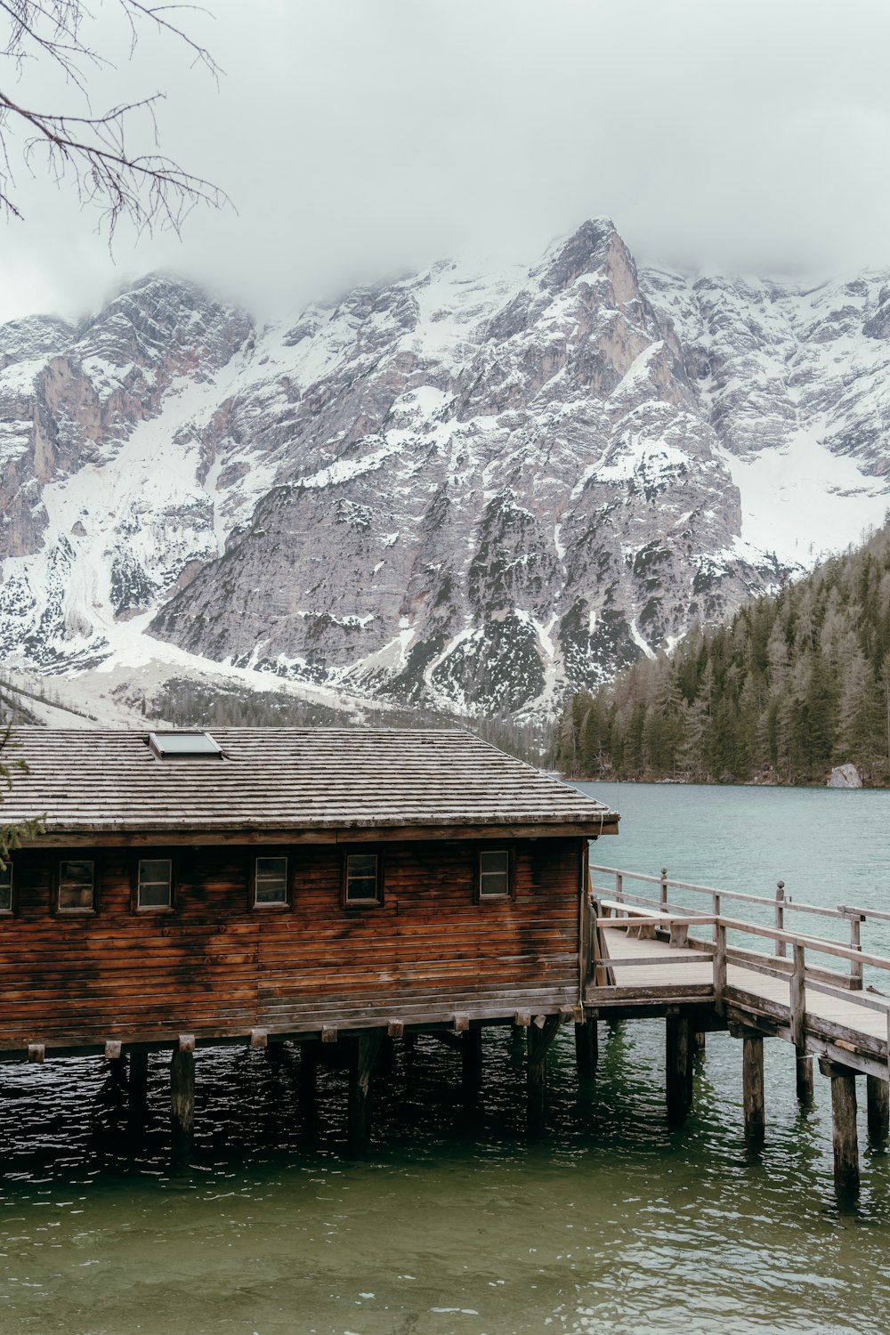 a wooden dock sitting next to a mountain covered in snow