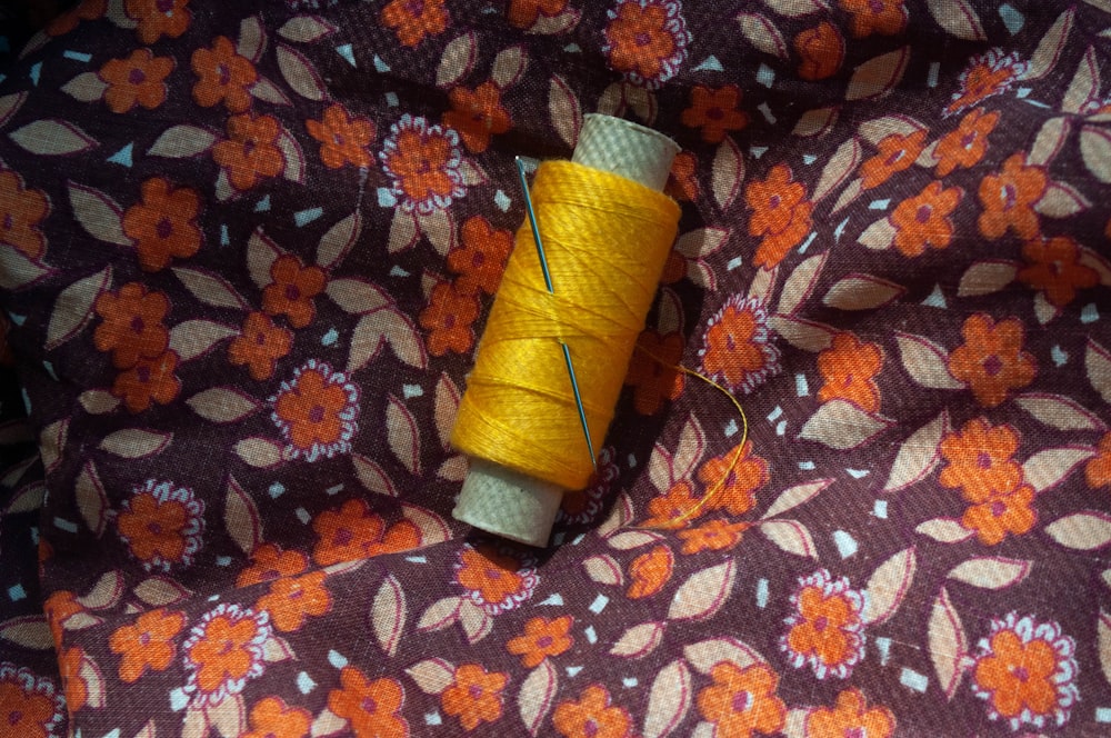 a spool of thread sitting on top of a flowery fabric