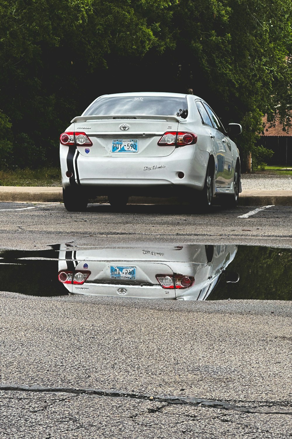 a white car parked in a parking lot next to a puddle of water