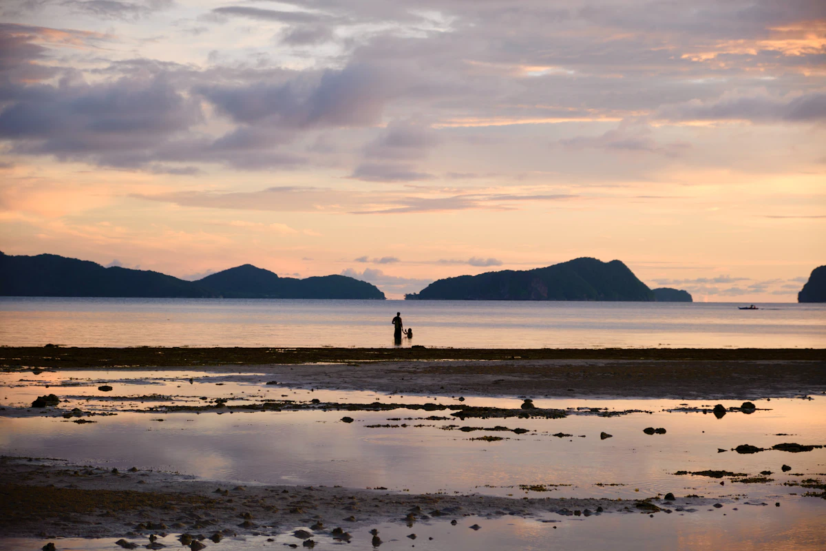 Person standing on a beach at sunset