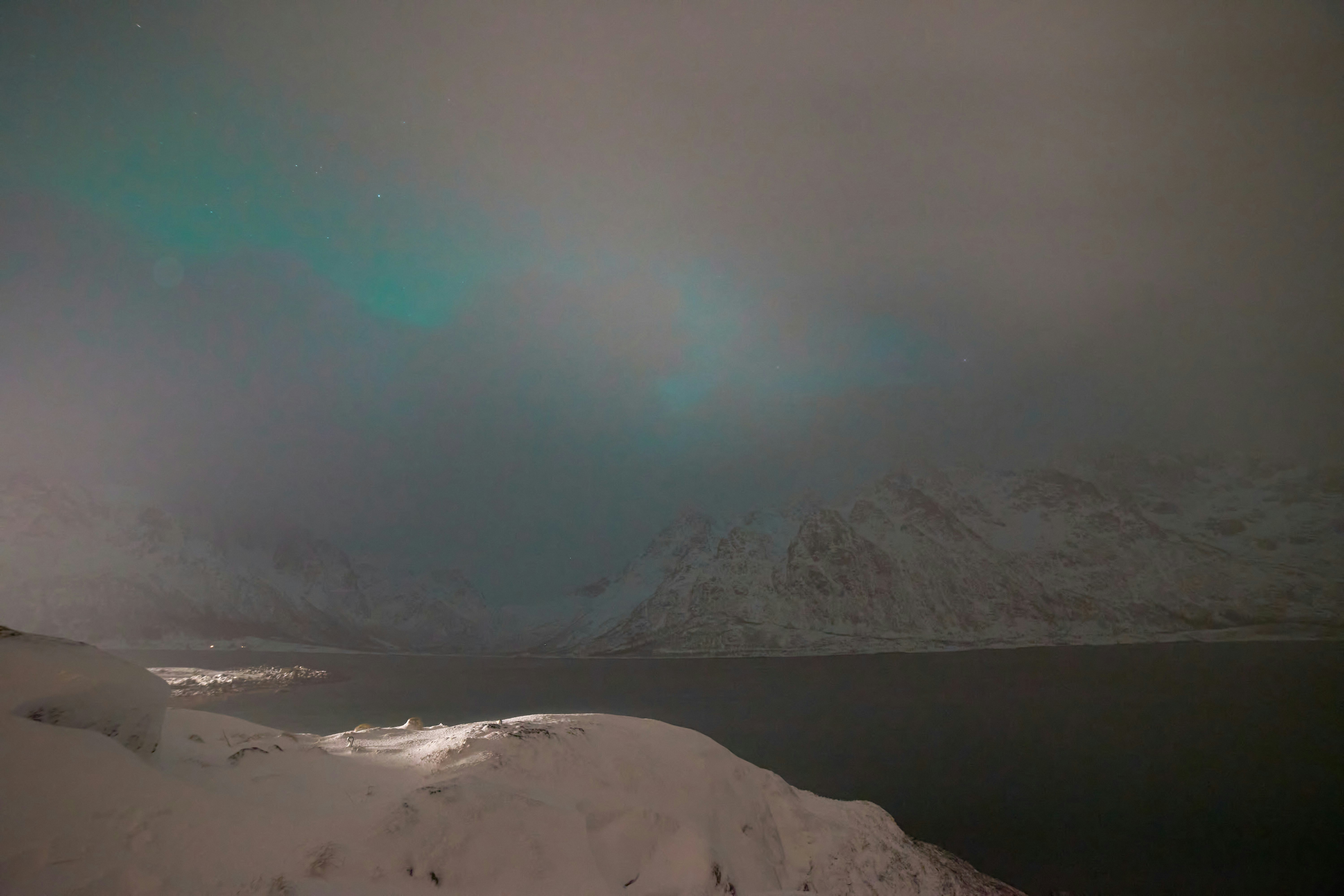 Aurora borealis over black snowy mountains, pitch dark night sky, deep shadows on frozen landscape