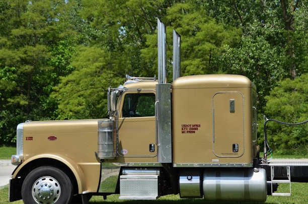 a yellow semi truck parked on the side of a road