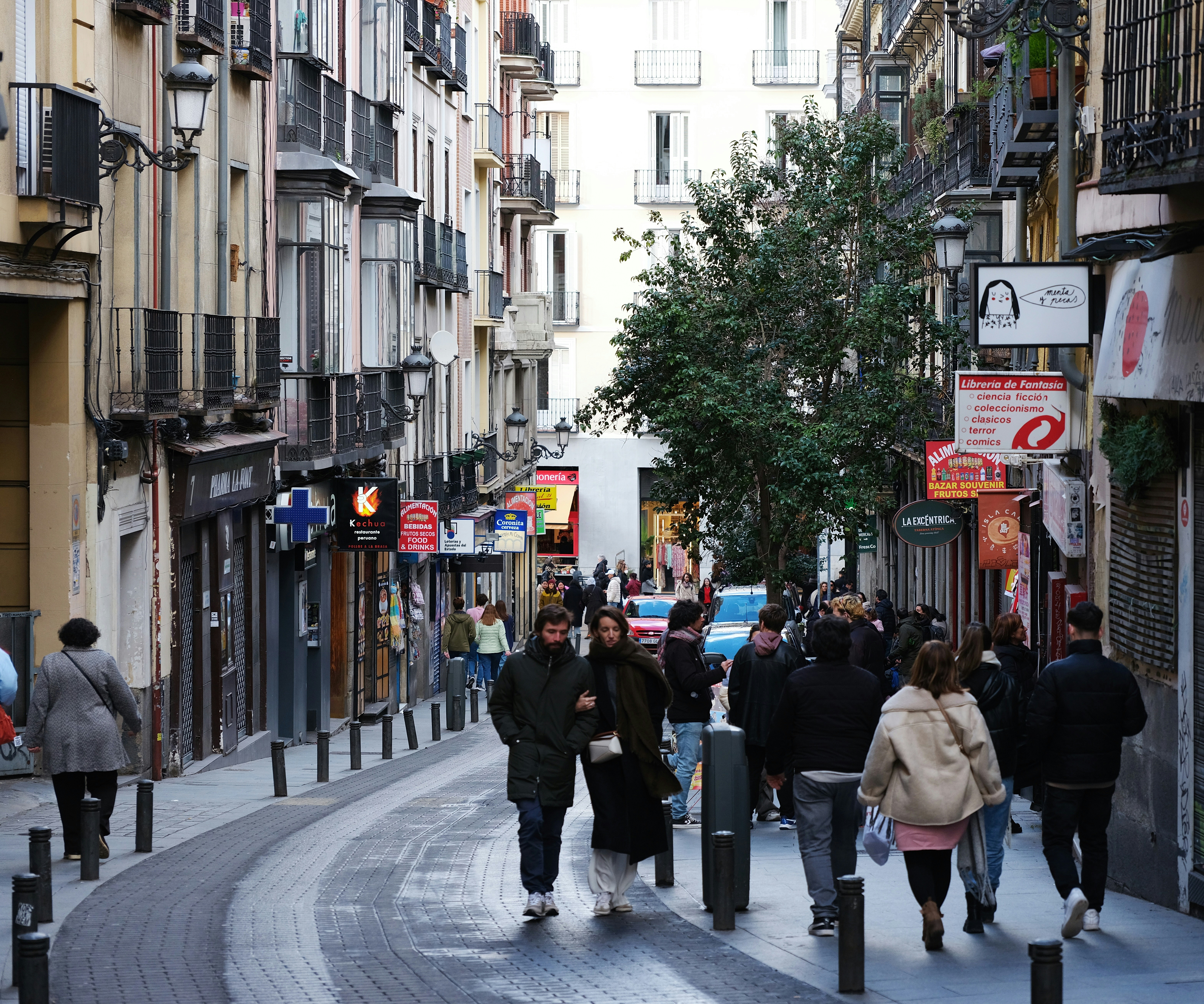 a group of people walking down a street next to tall buildings