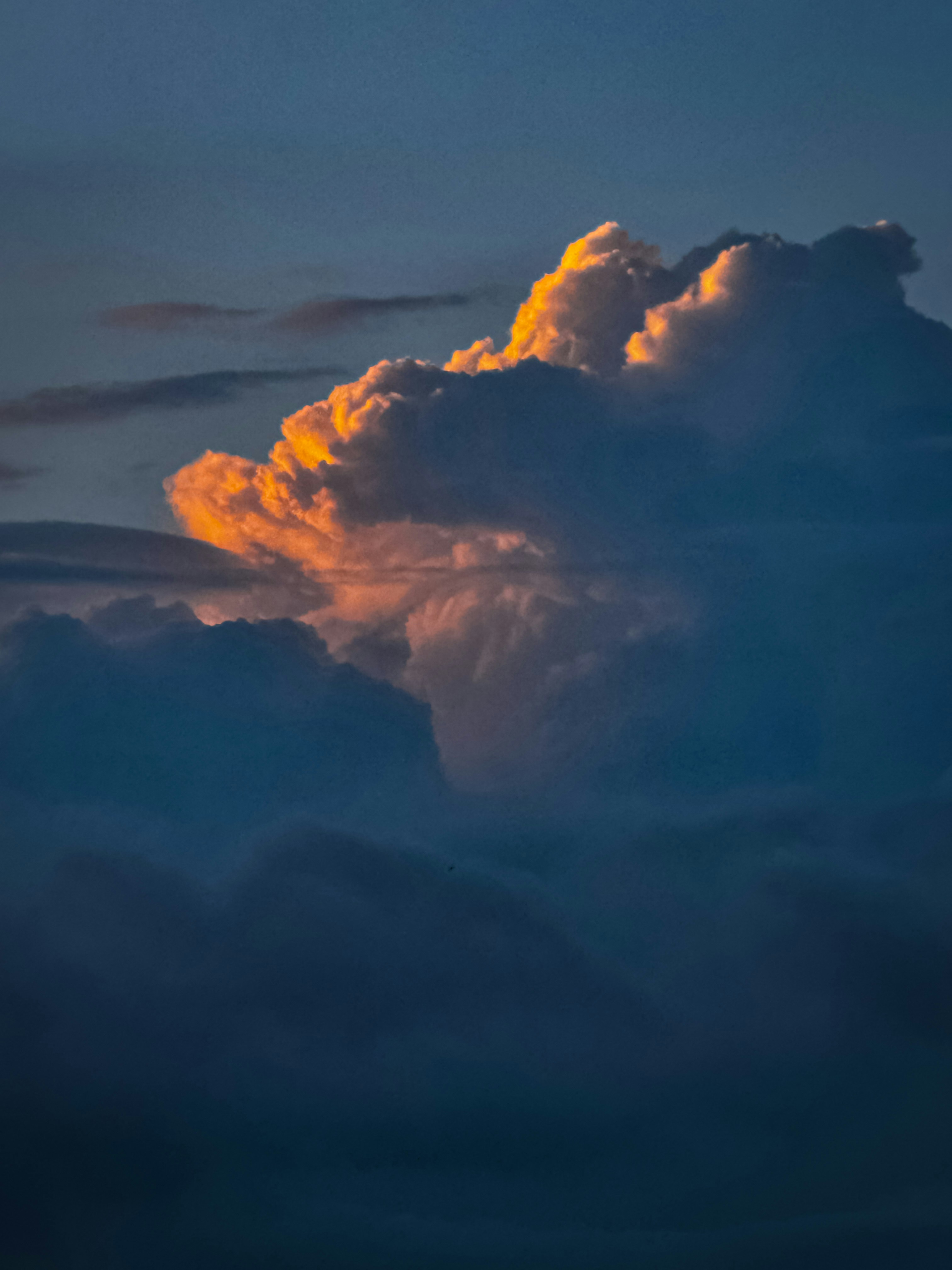 a plane flying through a cloudy sky at sunset