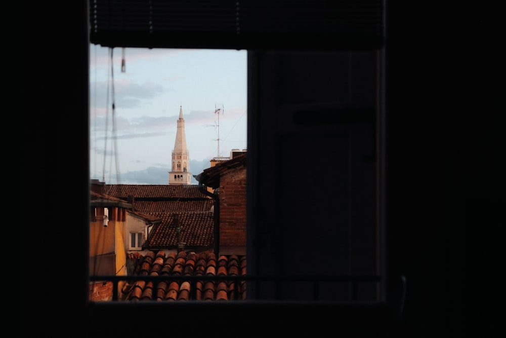 a view from a window of a building with a steeple in the background
