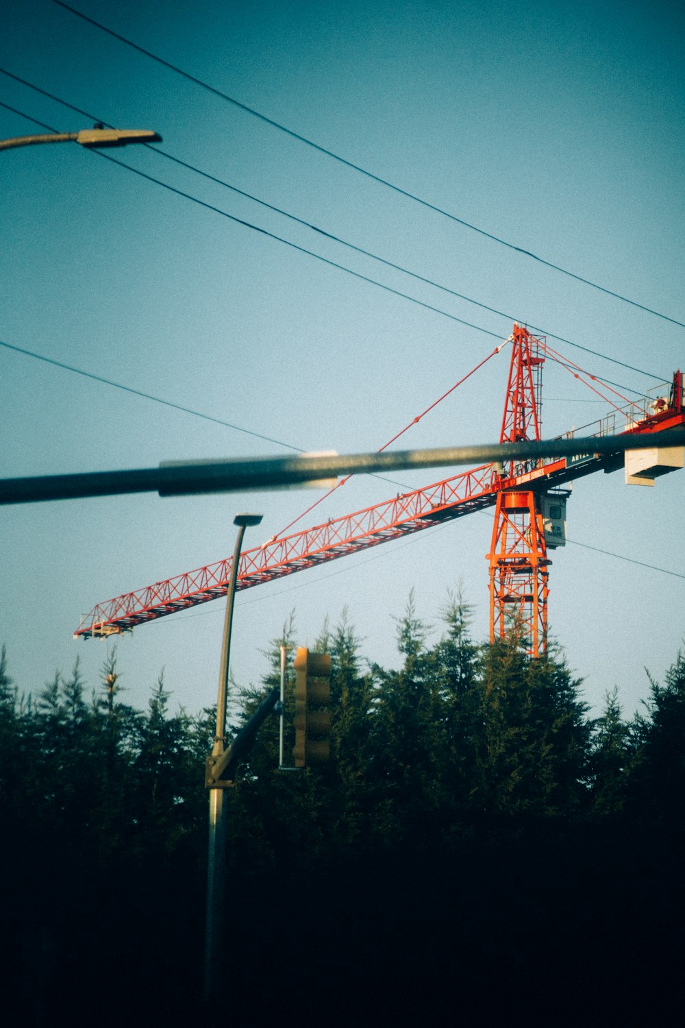 a red crane sitting on top of a building next to a traffic light