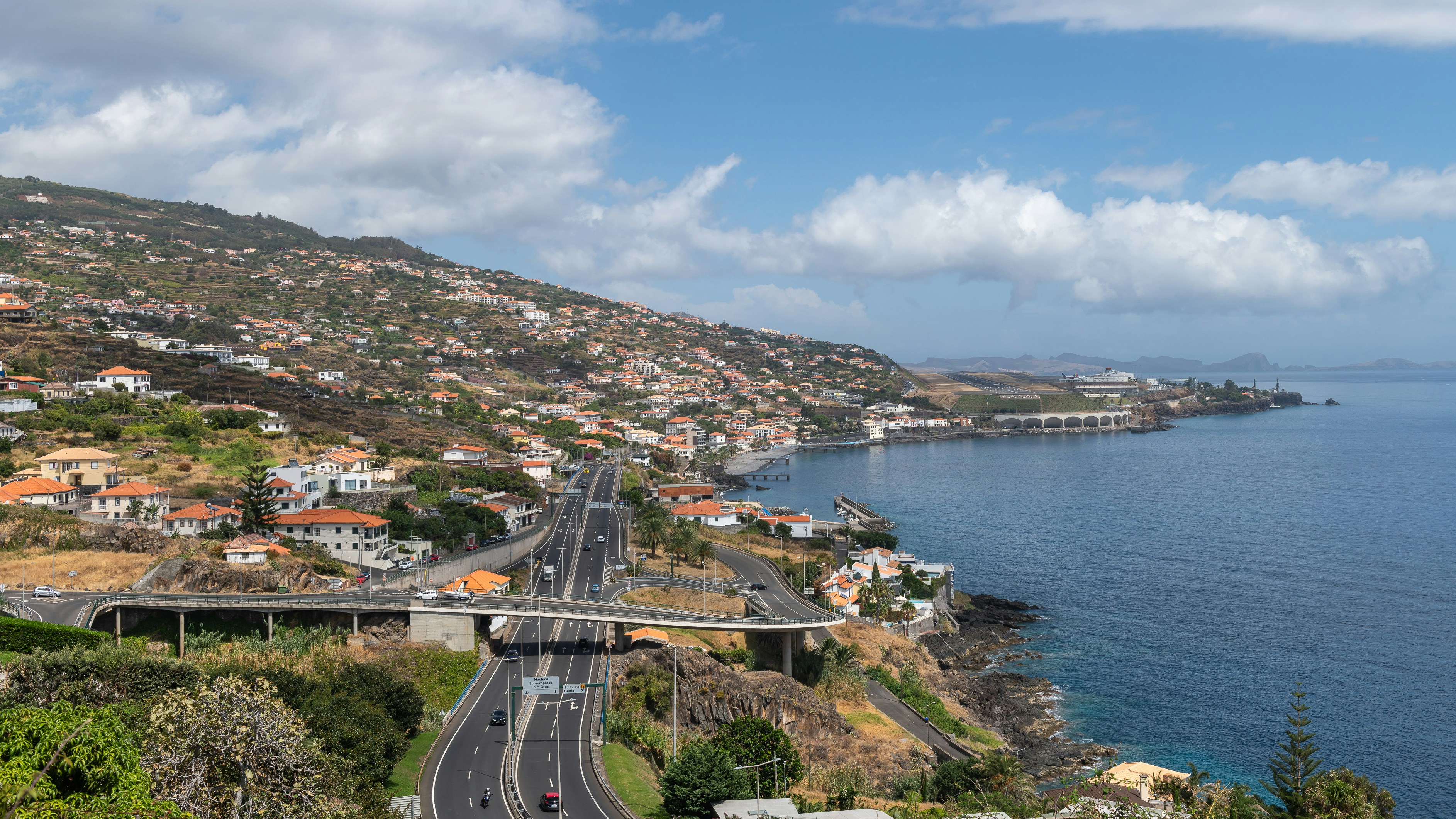 a view of a road going down a hill next to a body of water