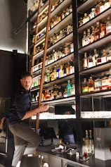 a man standing on a ladder in a bar