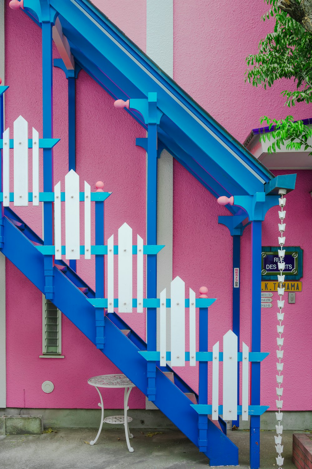 a blue and white stair case next to a pink building