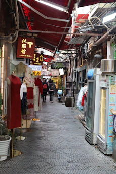 a narrow street with shops and people walking around