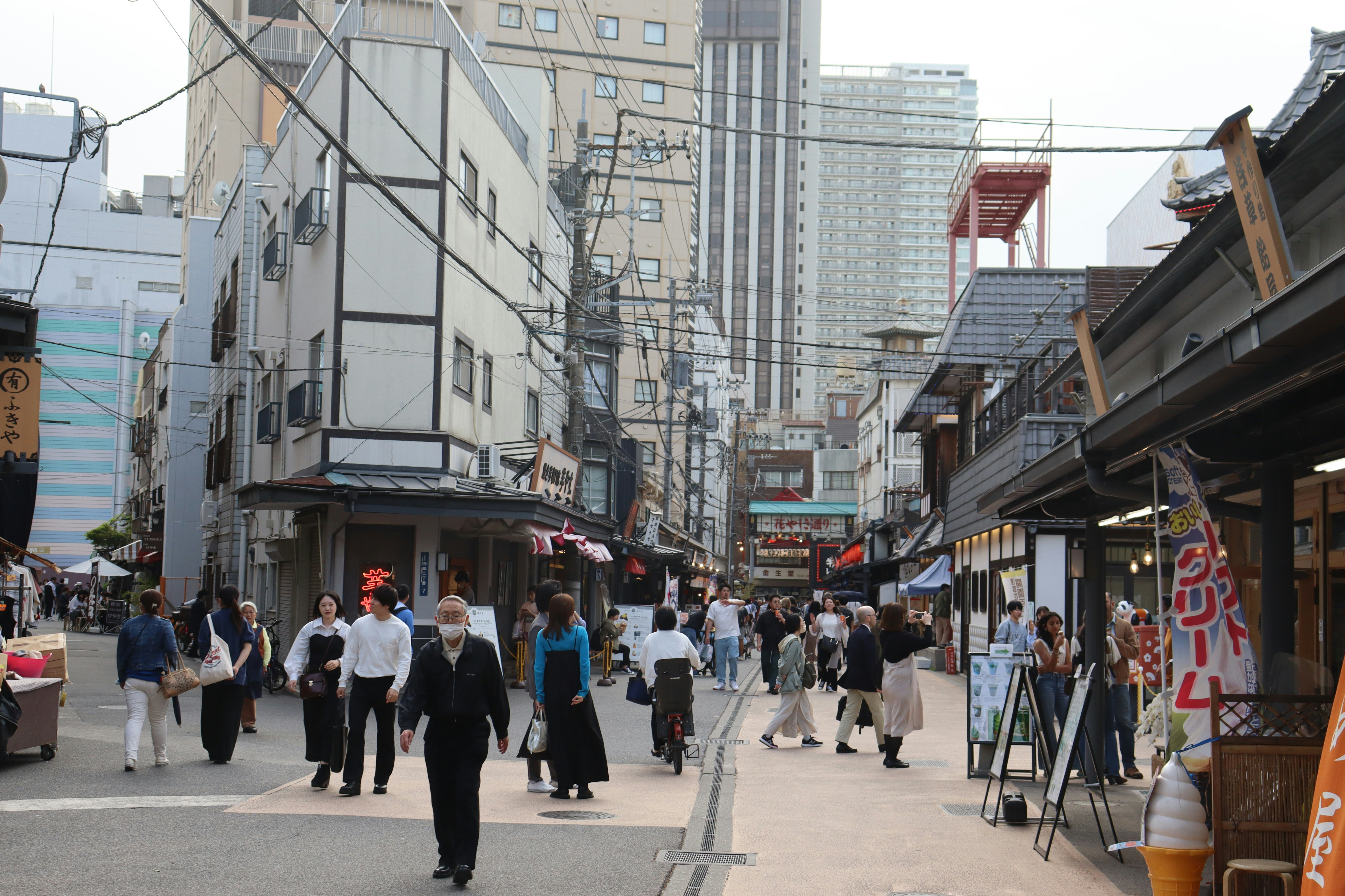 a group of people walking down a street next to tall buildings, 