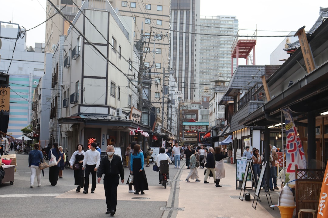 a group of people walking down a street next to tall buildings,