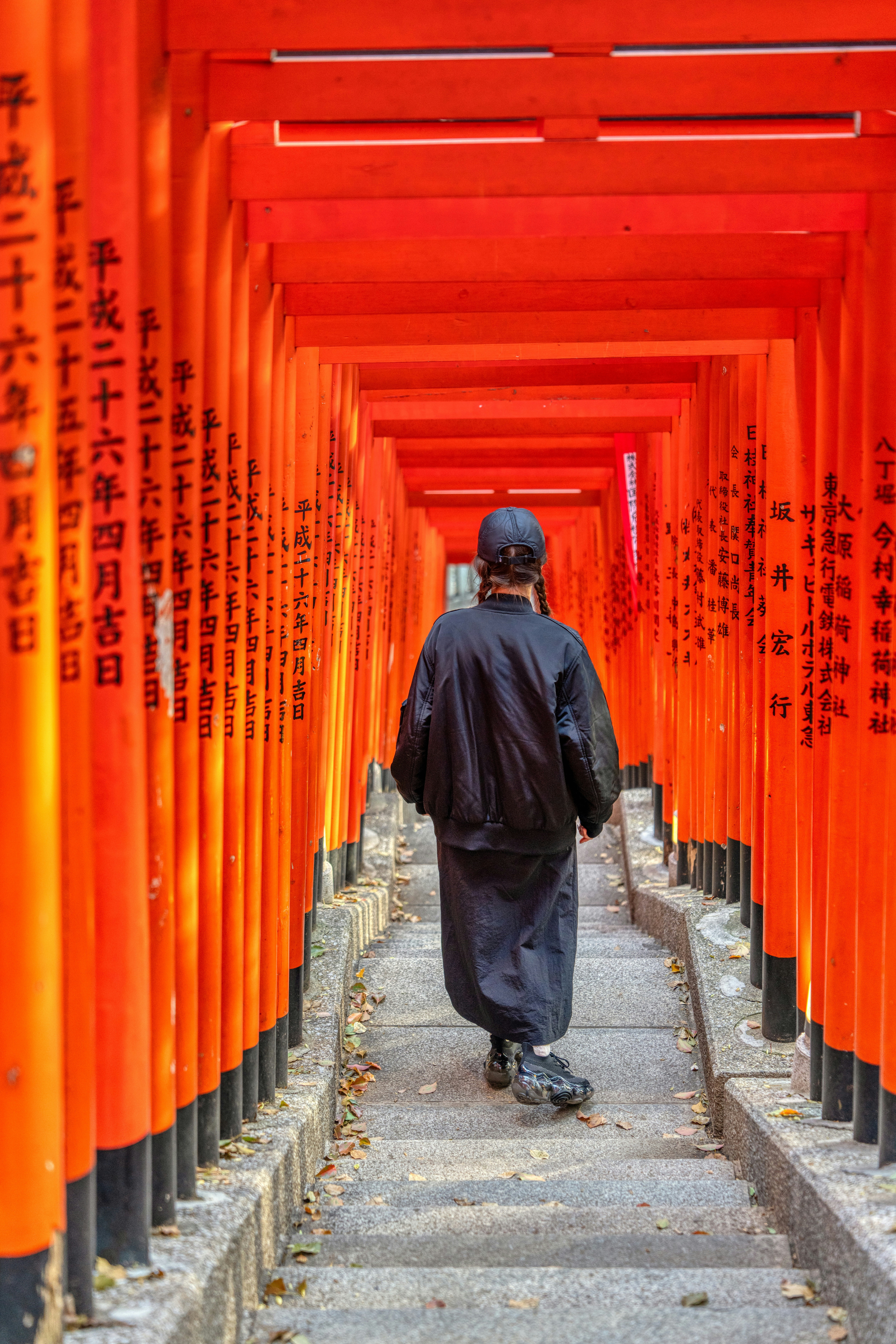 a man walking down a path lined with orange columns