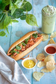 a sandwich on a table with chips and a drink