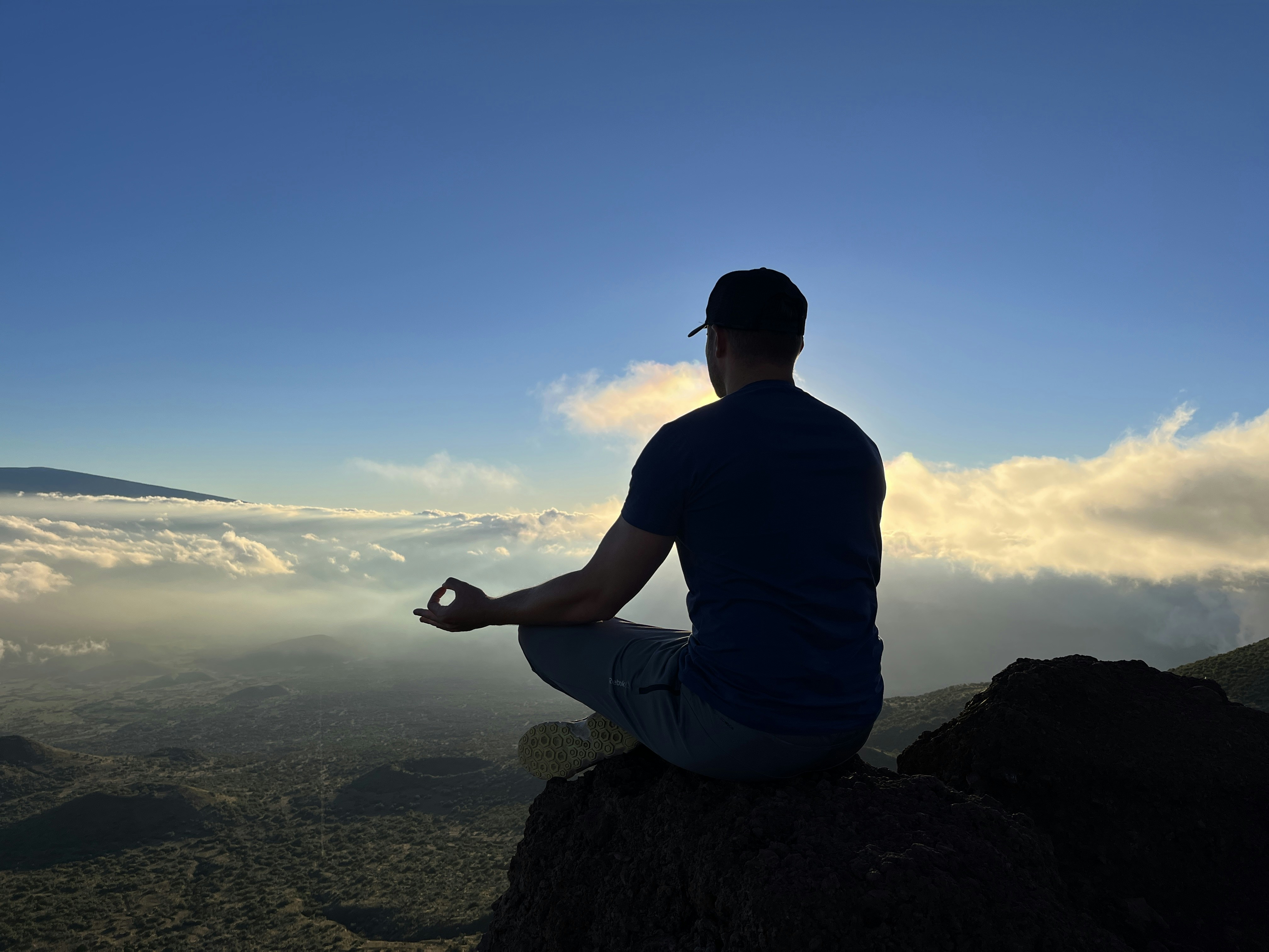 A man sitting on top of a mountain while meditating