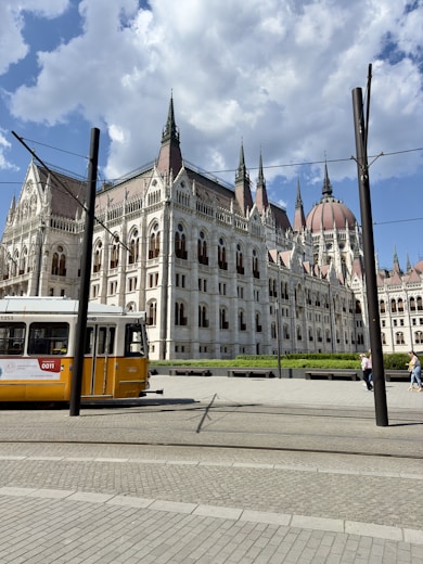 a yellow and white bus parked in front of a large building
