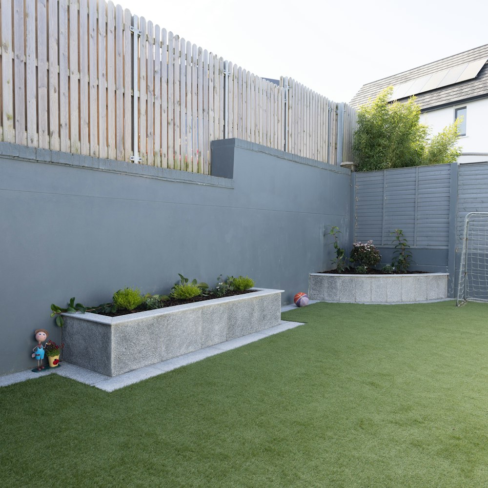 a backyard with artificial grass and a concrete planter