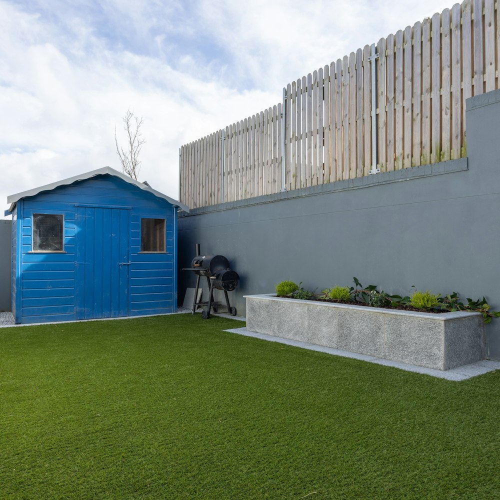 a small blue shed sitting next to a cement planter