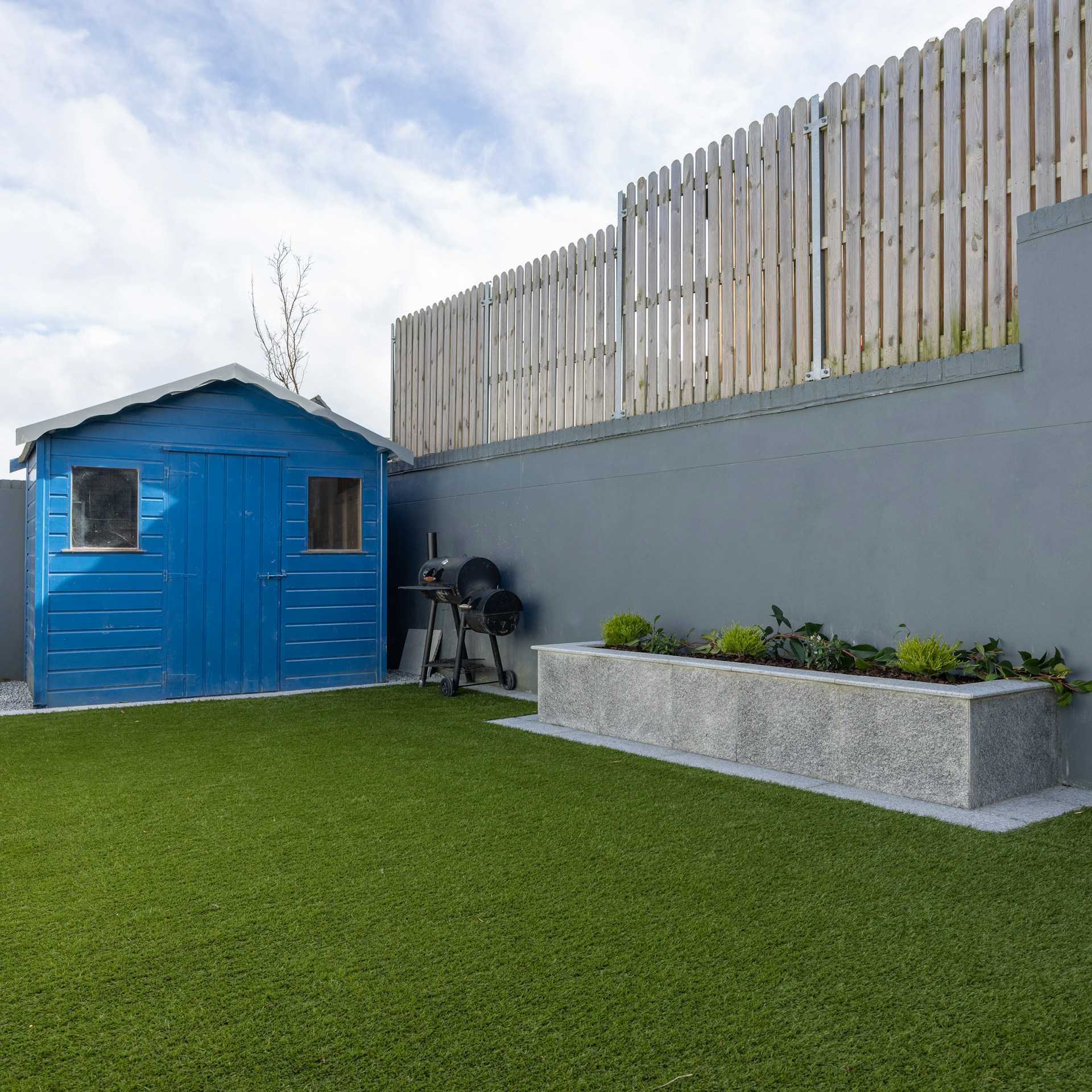a small blue shed sitting next to a cement planter