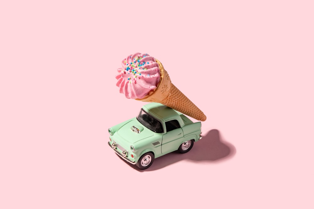an ice cream cone sitting on top of a green car
