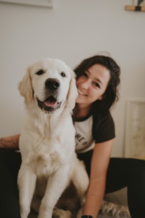 a woman sitting on a bed with a white dog