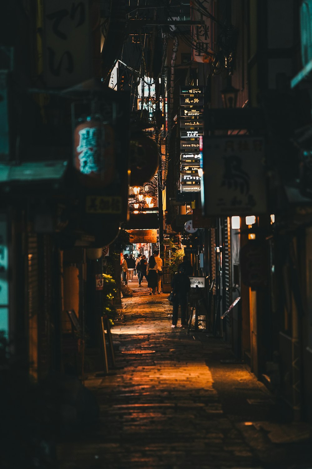 a narrow alley with people walking down it at night