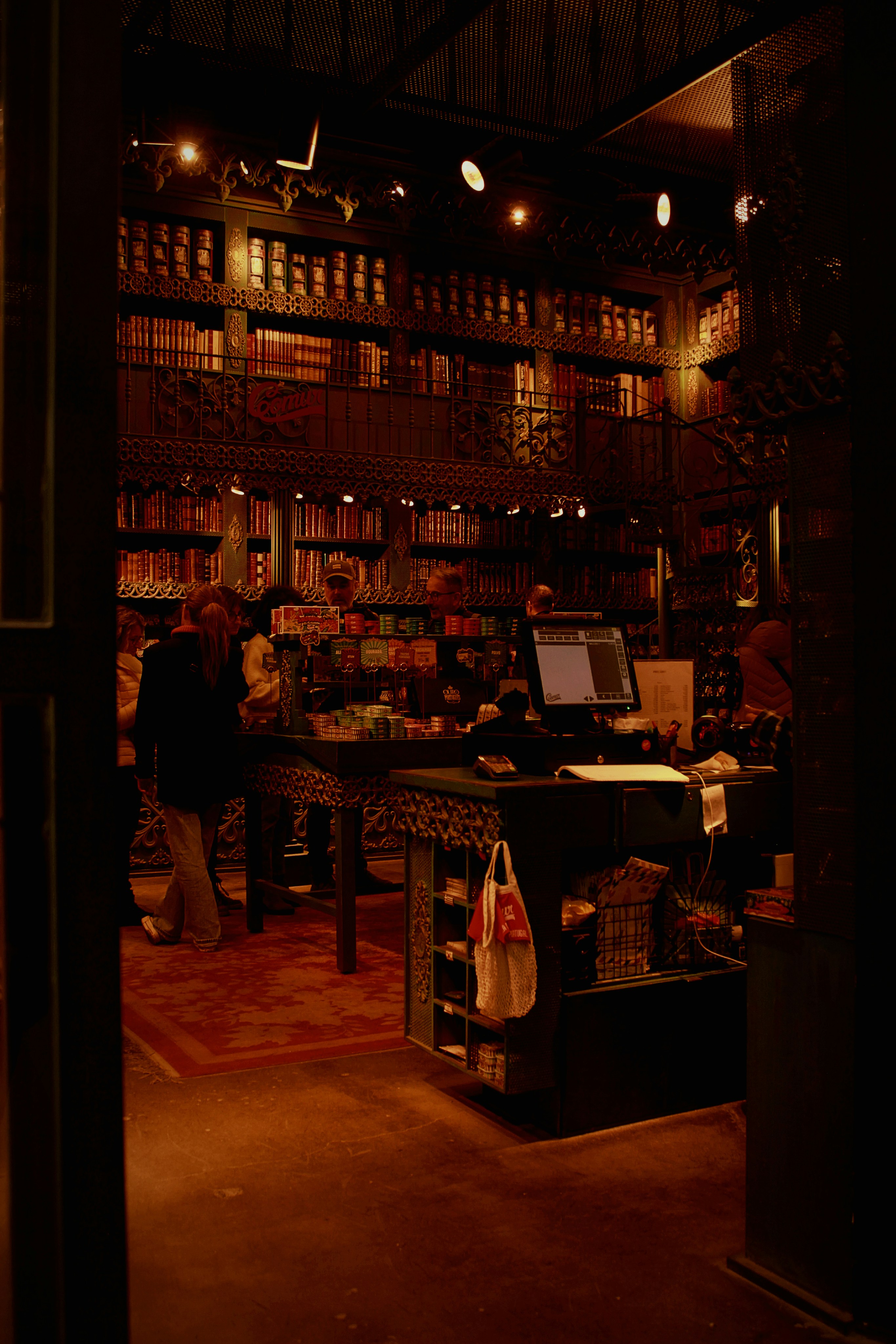 Dark atmospheric store with glowing festive ethnic wear on display, warm amber lighting, deep shadows on surrounding walls