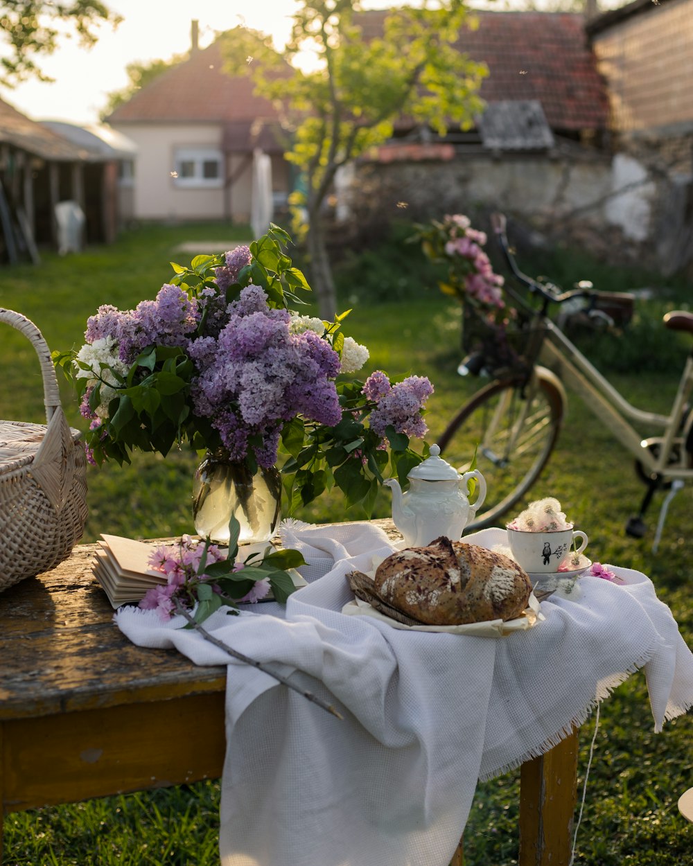 a table topped with a basket of flowers next to a bike