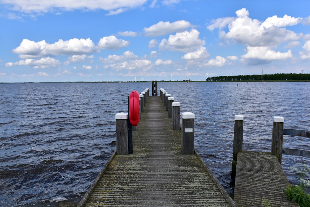 a long dock with a red umbrella on it